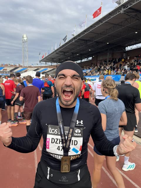 Dzhavid shouting in triumph on the running track of Amsterdam’s Olympic Stadium, a finisher’s medal round his neck and his name on his race bib.